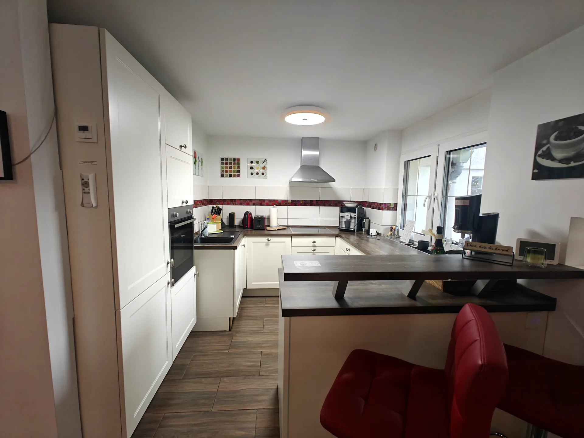 Bright kitchen with a counter, red bar stools and built-in appliances